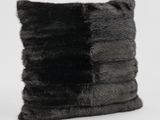the black and grey fur pillow is sitting on a white surface