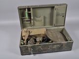 une vieille valise contenant des outils, posée sur une surface blanche