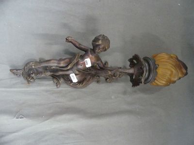 une statue représentant un garçon tenant une lampe, fixée sur un mur