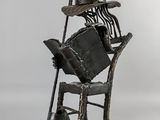 statue représentant un homme assis sur une chaise, coiffé d'un chapeau
