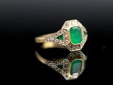 an emerald and diamond ring on a black surface