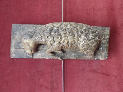 a sculpture of a sheep laying on a red surface