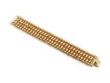 gros plan d'un bracelet en or sur fond blanc