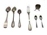 un grand nombre de cuillères et de fourchettes en argent sur une surface blanche