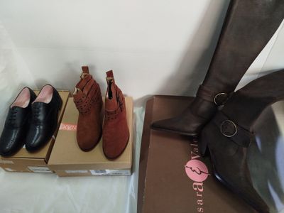 une paire de bottes noires et marron et une boîte de chaussures marron et noires
