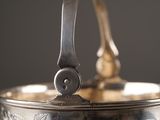 a silver bowl with a handle on it on a table