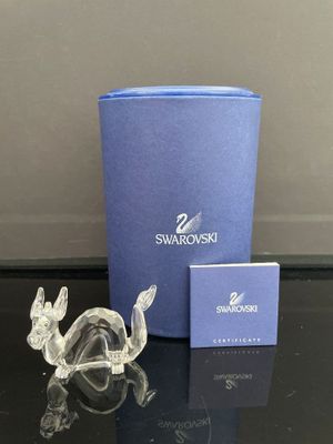 une figurine en verre transparent représentant une tortue assise à côté d'une boîte bleue