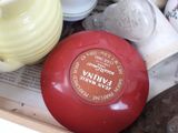 a red bowl sitting on top of a table next to other items
