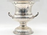 une coupe ancienne en métal argenté, munie d'anses et posée sur un socle