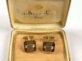 two pairs of cufflinks in a box on a white surface