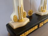 two white and gold vases with a chandelier hanging from them