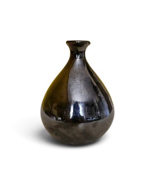 un vase noir posé sur une surface blanche