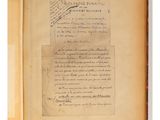 an old book with writing on it and a piece of paper on top of it