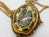 une photo d'un collier en or sur lequel figure le portrait d'une femme