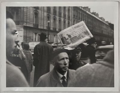photographie en noir et blanc d'un homme tenant un journal au milieu d'une foule