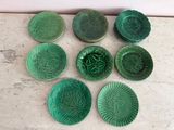 six green plates with designs on them sitting on a marble surface
