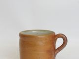 a close up of a brown cup with a handle on a white background