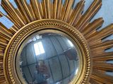 a gold sunburst mirror on the wall of a room