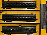 three black train cars on display in a yellow case