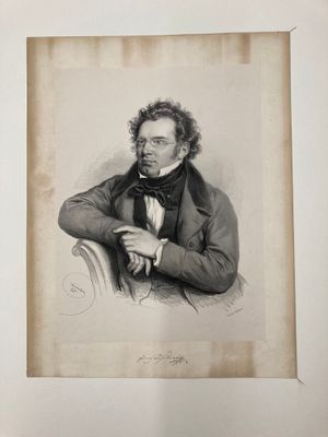 portrait d'un homme en costume et nœud papillon, assis sur une chaise