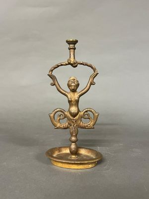 une image représentant un bougeoir en or surmonté d'une statuette