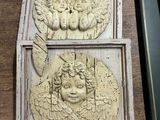 deux plaques représentant des anges posées sur une table en bois