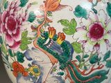a vase with a bird and flowers on it on a stand
