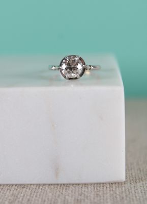 un gros plan d'une bague en diamant posée sur un bloc de marbre blanc
