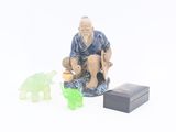 une figurine représentant un vieil homme assis sur une caisse