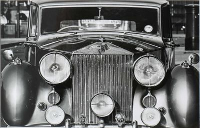 an old black and white photo of a classic car with a clock on the front of it