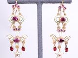 two pairs of earrings with garnets on a stand