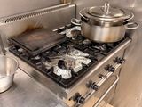 une cuisinière sur laquelle sont posées des casseroles et des poêles, dans une cuisine