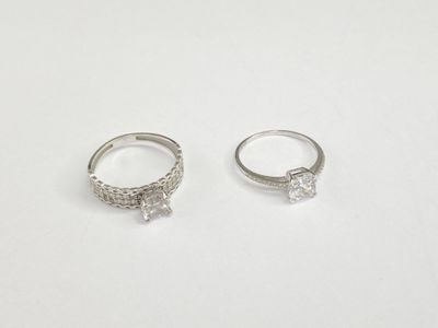 two silver rings with diamonds on them on a white surface