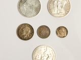 Plusieurs pièces de monnaie différentes sont alignées sur une surface blanche