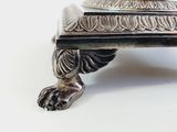 a silver plate with a lion on it on a white surface