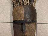 un masque accroché au mur, orné de plumes