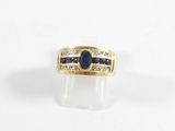gros plan d'une bague en or avec une pierre bleue et des diamants