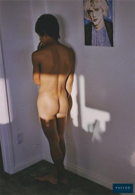 un homme nu debout devant un mur sur lequel est accroché un tableau