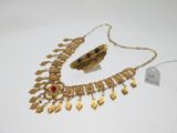 un gros plan d'un collier et d'un bracelet en or posés sur une surface blanche