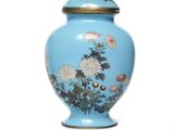 un vase bleu sur lequel sont peintes des fleurs, sur un fond blanc