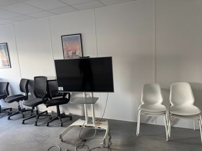 trois chaises dans une pièce où est accrochée une télévision à écran plat au mur