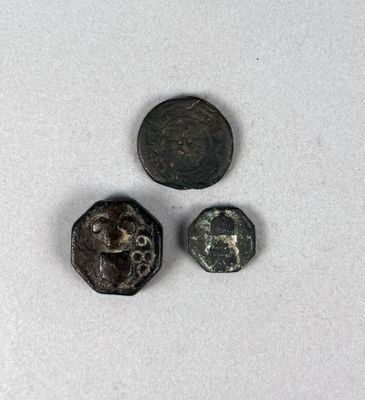 un gros plan d'une pièce de monnaie et de deux autres pièces posées sur une surface blanche