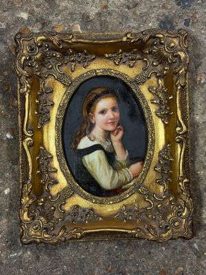 une vieille photo d'une jeune fille dans un cadre doré, posée par terre
