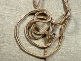 a gold necklace with a snake on it on a beige cloth