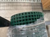 a green wire fence wrapped in plastic on the ground