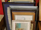 de nombreuses œuvres d'art encadrées posées par terre à côté d'un fauteuil