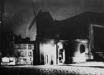 photo nocturne d'une rue avec un immeuble et un clocher
