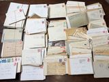 pile of old letters and envelopes sitting on a wooden table