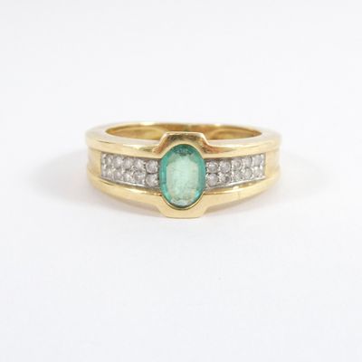 a close up of a gold ring with a green stone and diamonds