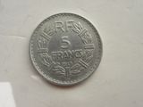 une pièce de 5 francs posée sur une surface blanche